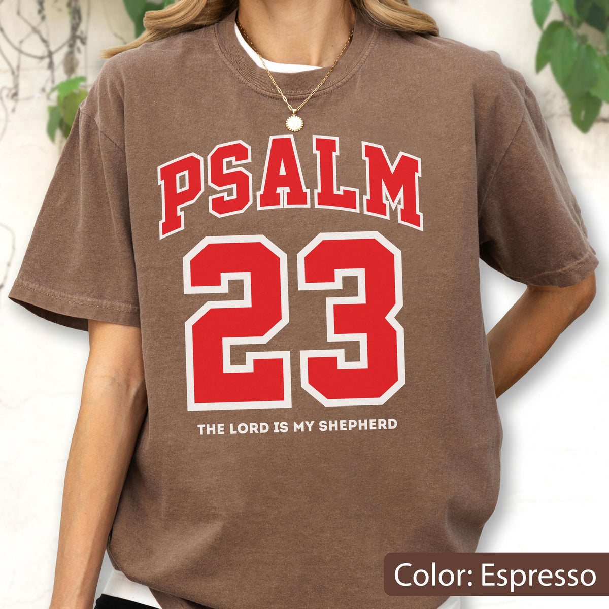 May include: An espresso brown short-sleeve t-shirt featuring the red text PSALM 23 in a collegiate font, with the number 23 in large red block lettering below it, and the white text THE LORD IS MY SHEPHERD printed at the bottom of the graphic.