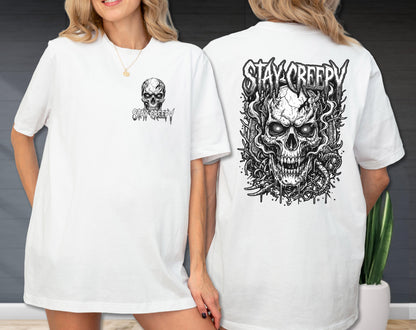 May include: A white t-shirt featuring a black and white graphic print. The front displays a small skull with the text "STAY CREEPY". The back features a large, detailed illustration of a skull surrounded by smoke and vines with "STAY CREEPY" text.
