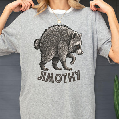 May include: A heather gray t-shirt featuring a detailed illustration of a raccoon with intricate leaf-like patterns in its fur. Below the raccoon, the name JIMOTHY is printed in bold, dark, sans-serif capital letters on the front of the shirt.