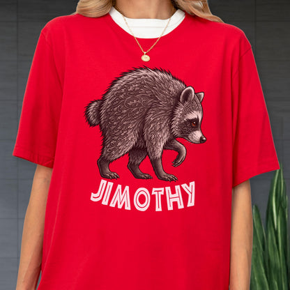May include: A bright red t-shirt featuring a graphic illustration of a raccoon with intricate leaf-like patterns in its fur. Below the raccoon, the name JIMOTHY is printed in bold, white, sans-serif capital letters. The shirt has a crew neckline.