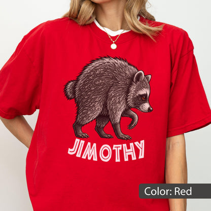 May include: A bright red short-sleeved t-shirt featuring a graphic of a raccoon with intricate leaf-like patterns in its fur. Below the raccoon, the name JIMOTHY is printed in bold, light pink capital letters. The shirt has a crew neckline.