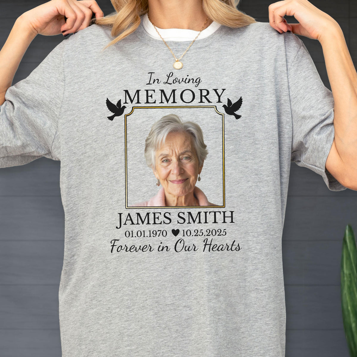 May include: A heather gray t-shirt featuring a memorial design with the text In Loving Memory, a framed photograph of an older person, the name JAMES SMITH, the dates 01.01.1970 and 10.25.2025 separated by a heart, and the text Forever in Our Hearts.