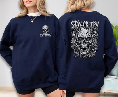 May include: A navy blue long-sleeve sweatshirt featuring a small white skull graphic and the text "STAY CREEPY" on the front left chest, and a large, detailed white skull illustration with the text "STAY CREEPY" printed on the back.