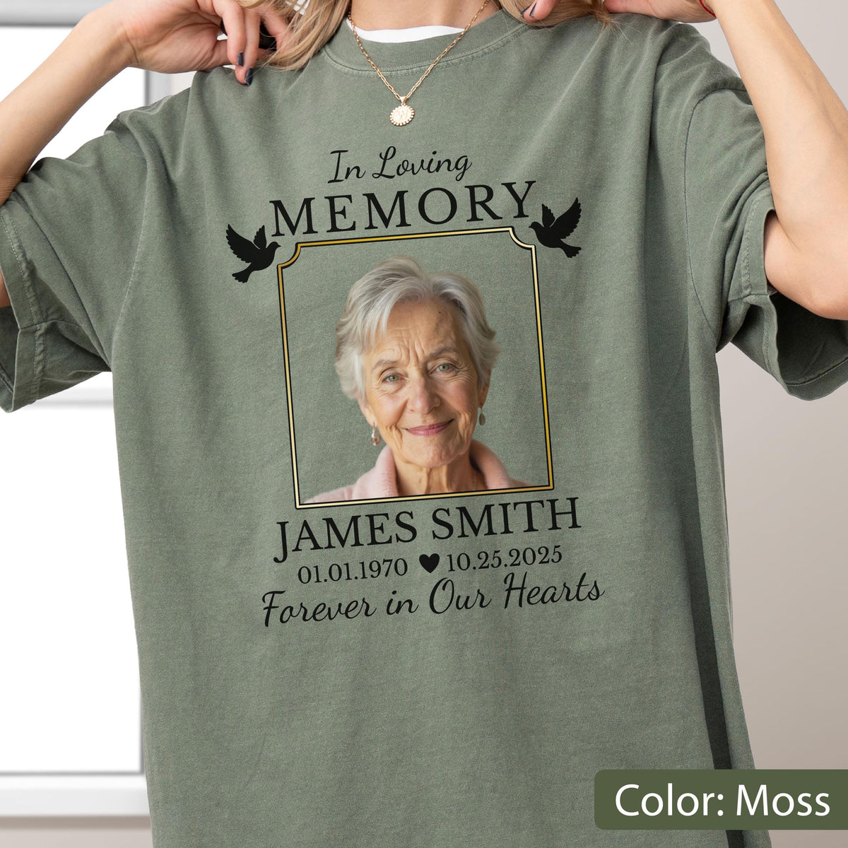 May include: A moss green t-shirt featuring a memorial graphic with a photograph of an older person inside a gold-bordered frame. The text reads In Loving Memory, JAMES SMITH, 01.01.1970, 10.25.2025, and Forever in Our Hearts, with two black doves.