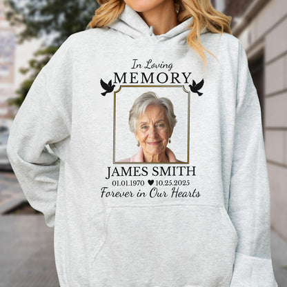 May include: A light gray hooded sweatshirt featuring a memorial graphic with a photograph of an older person. The text reads In Loving Memory, James Smith, 01.01.1970, 10.25.2025, and Forever in Our Hearts, accompanied by two black bird silhouettes.