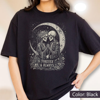 May include: A black t-shirt featuring a graphic print of two skeletons holding hands under a crescent moon. The skeletons are surrounded by flowers and stars. Below the illustration, the text reads "FOREVER & ALWAYS" in a decorative font.