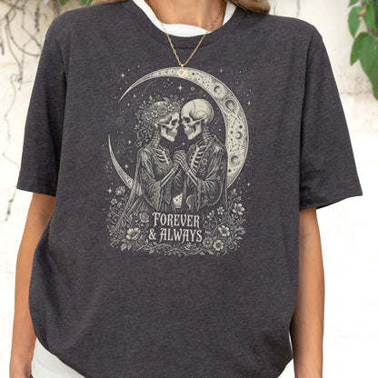 May include: A dark charcoal gray short-sleeve t-shirt featuring a graphic print of two skeletons holding hands under a crescent moon. The design includes floral accents and the text "FOREVER & ALWAYS" in a decorative font centered below the figures.