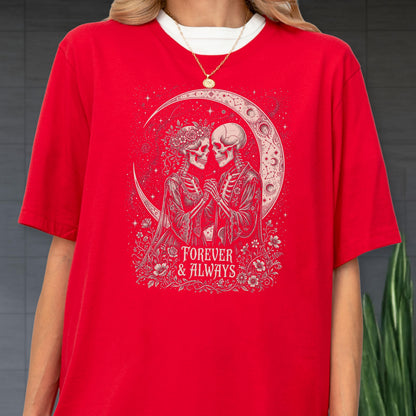 May include: A bright red t-shirt featuring a graphic print of two skeletons holding hands under a crescent moon. The design includes floral accents and the text "FOREVER & ALWAYS" in a decorative font. The shirt has short sleeves and a crew neck.