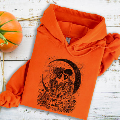 May include: A bright orange hooded sweatshirt featuring a black graphic print of two skeletons facing each other under a crescent moon, surrounded by floral details and the text "FOREVER & ALWAYS" printed in a stylized font on the front.
