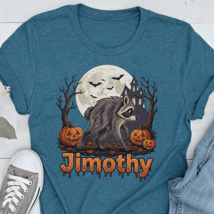 May include: A teal t-shirt featuring a graphic of a raccoon standing between two bare trees, three orange jack-o'-lanterns, a large full moon, bats, and a dark house silhouette. The name Jimothy is printed below in an orange, dripping font.