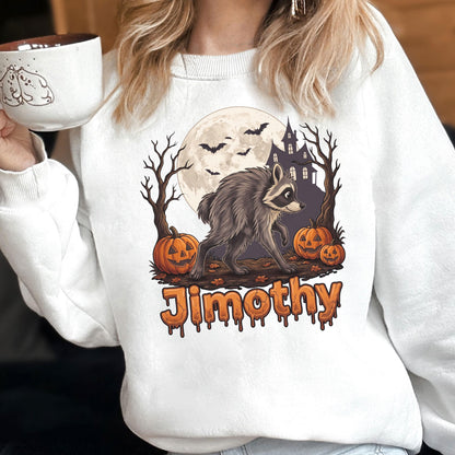 May include: A white sweatshirt featuring a graphic of a raccoon walking in front of a full moon, a haunted house, bare trees, and jack-o'-lanterns. The name "Jimothy" is printed below in orange, dripping-style lettering. The design has a spooky theme.