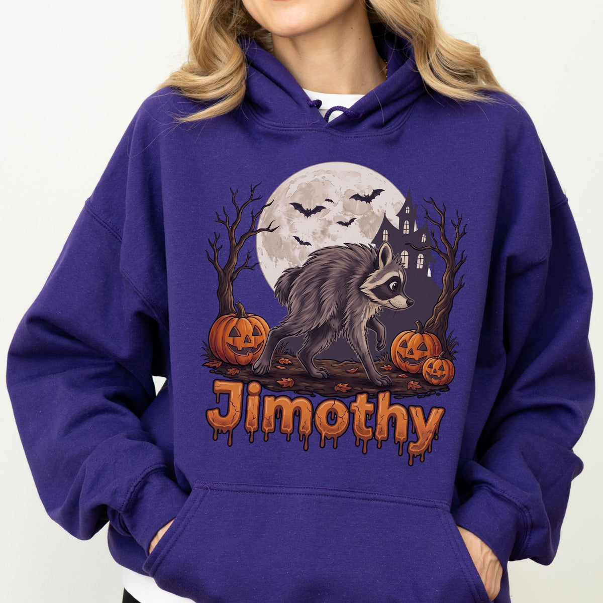 May include: A deep purple hooded sweatshirt featuring a graphic print of a raccoon standing in front of a full moon, a haunted house, bare trees, and jack-o'-lanterns. The name Jimothy is printed in orange, dripping-style lettering below the graphic.