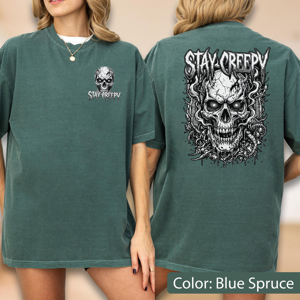 May include: A blue spruce t-shirt featuring a small skull graphic on the front left chest with the text STAY CREEPY. The back displays a large, detailed illustration of a skull surrounded by swirling smoke and vines with the text STAY CREEPY.