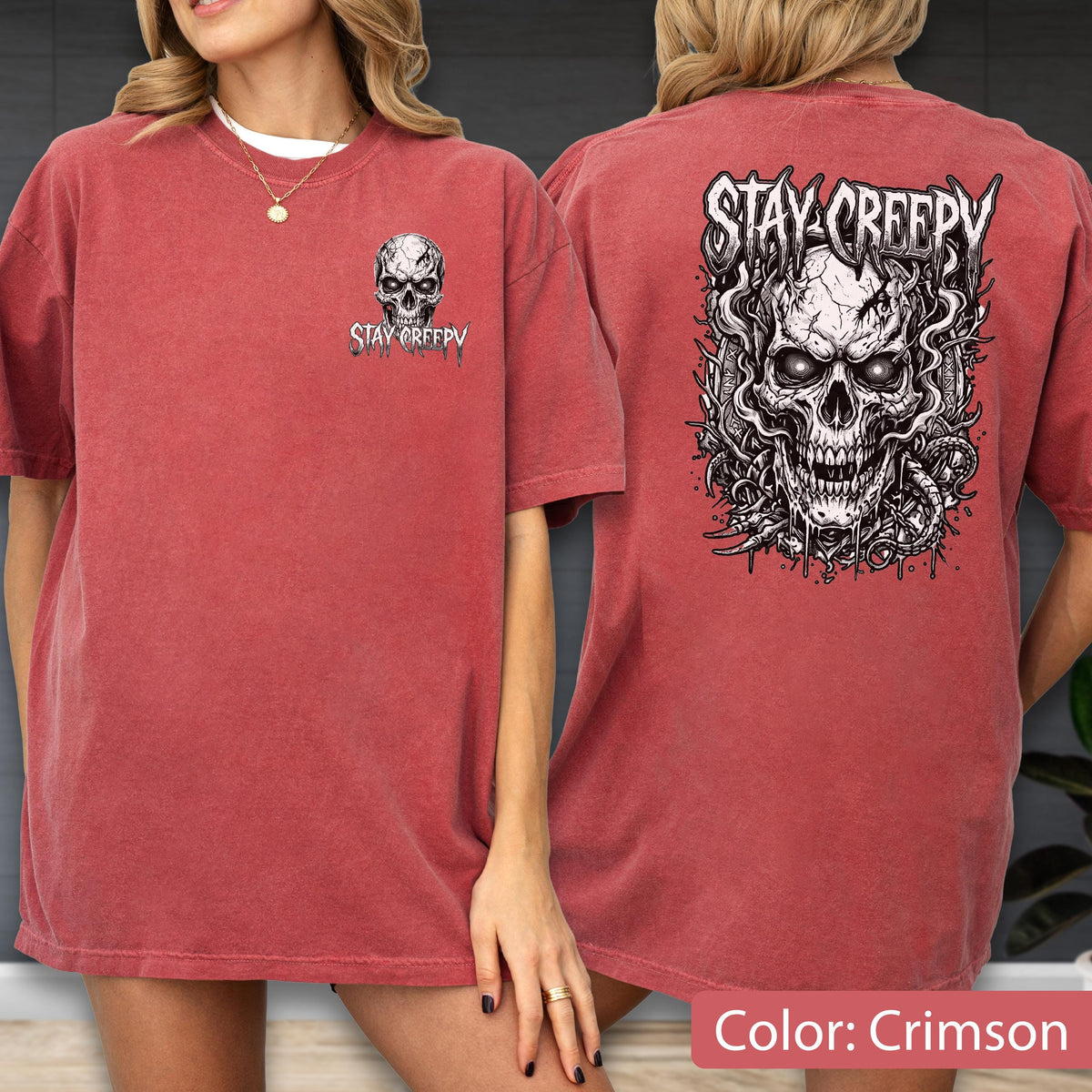 May include: A crimson short-sleeve t-shirt featuring a small black and white skull graphic on the front left chest with the text STAY CREEPY. The back displays a large, detailed black and white illustration of a skull with the text STAY CREEPY.