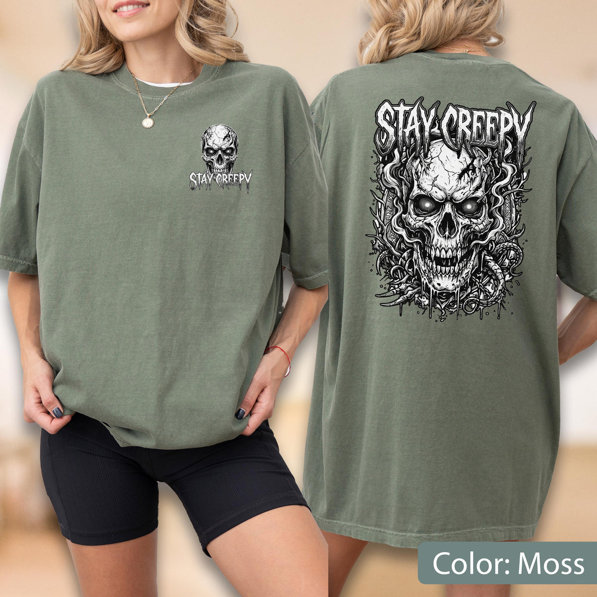 May include: An olive green t-shirt featuring a small skull graphic and the text "STAY CREEPY" on the front left chest. The back of the shirt displays a large, detailed black and white illustration of a skull surrounded by smoke and vines.