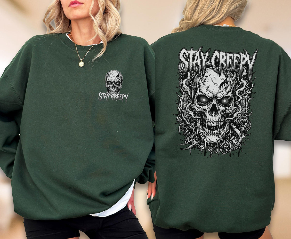 May include: A dark green crewneck sweatshirt featuring a small graphic of a skull and the text STAY CREEPY on the front left chest, and a large, detailed black and white illustration of a skull with swirling smoke and the text STAY CREEPY on the back.
