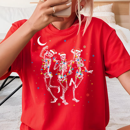 May include: A bright red short-sleeved t-shirt featuring a graphic of three white skeletons wearing Santa hats. The skeletons are tangled in colorful Christmas lights, surrounded by small white crescent moon, star, and snowflake icons.