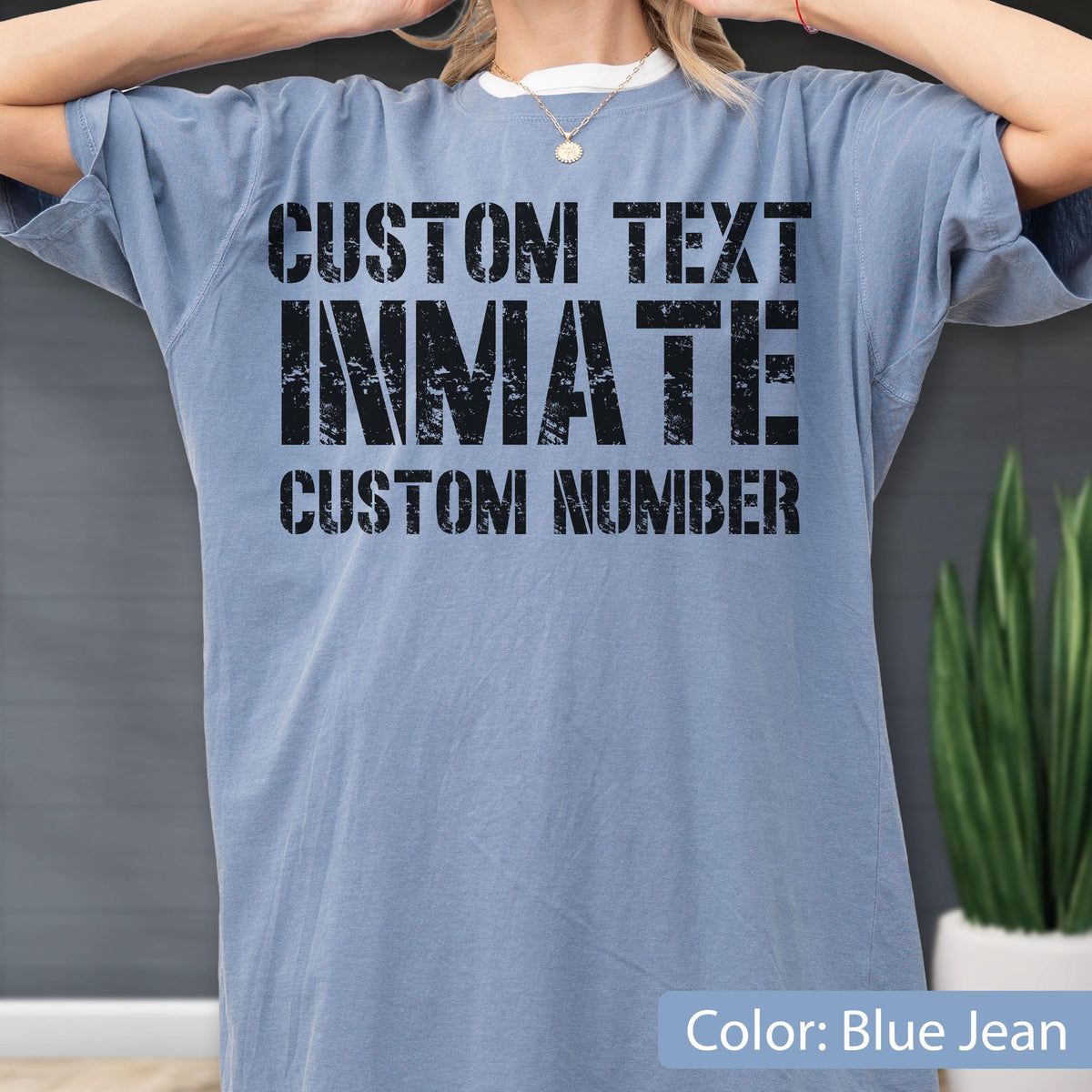 May include: A blue jean colored short-sleeve t-shirt featuring black distressed lettering on the front. The text reads CUSTOM TEXT, INMATE, and CUSTOM NUMBER in a bold, block font style. The shirt has a crew neckline and a relaxed fit.