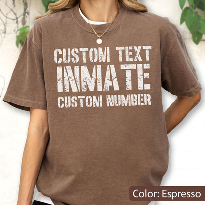 May include: A brown short-sleeve t-shirt featuring white distressed-style text that reads CUSTOM TEXT, INMATE, and CUSTOM NUMBER. The shirt has a crew neckline and a relaxed fit, showcasing a weathered graphic design on the front chest area.