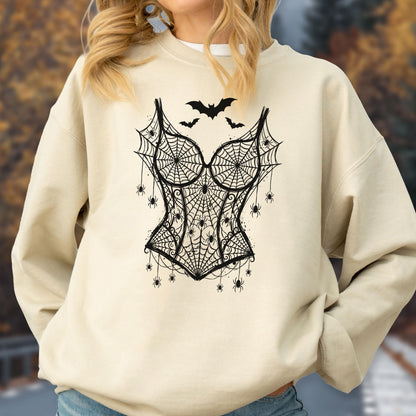 May include: A beige crewneck sweatshirt featuring a black graphic print of a corset made from spiderwebs. The design includes multiple small spiders hanging from the webbed corset and three bats flying above the bodice in the center chest area.