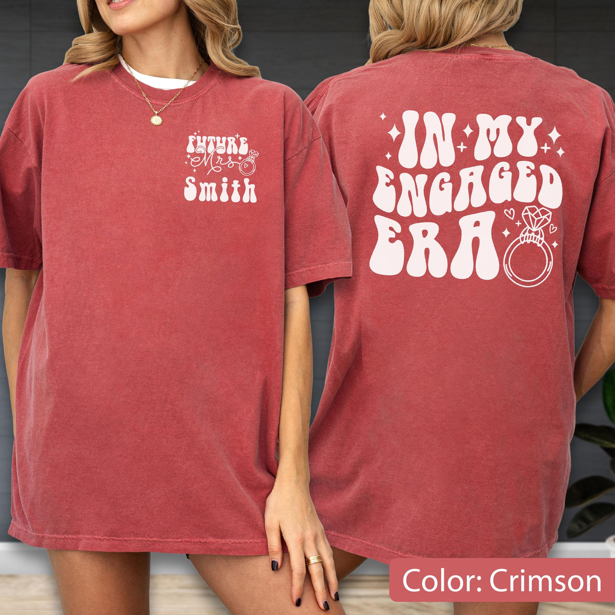 May include: A crimson short-sleeve t-shirt featuring white text. The front displays "Future Mrs Smith" with a ring icon. The back features the text "IN MY ENGAGED ERA" in a large, wavy font, accompanied by small star and heart icons and a diamond ring graphic.