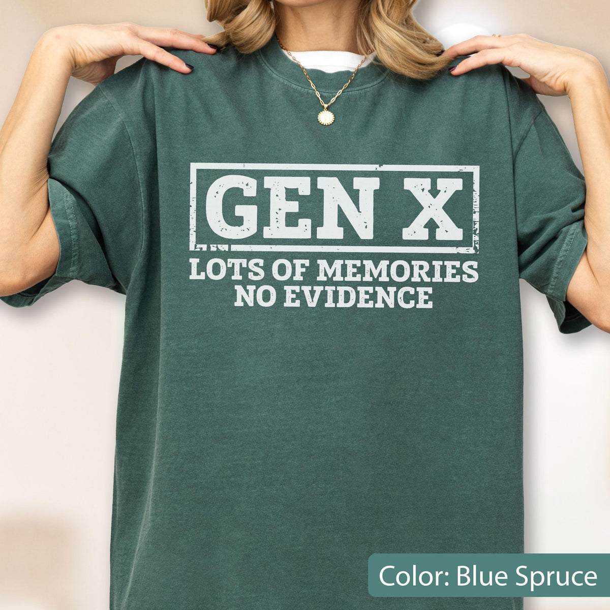 May include: A blue spruce colored t-shirt featuring white distressed text that reads GEN X LOTS OF MEMORIES NO EVIDENCE. The text is enclosed in a rectangular border. The shirt has a crew neckline and short sleeves, providing a casual appearance.