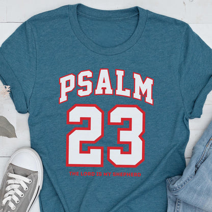 May include: A heathered teal blue short-sleeve t-shirt featuring the white text PSALM 23 in a collegiate font above the large white number 23 with a red outline. Below the number, the text THE LORD IS MY SHEPHERD is printed in small red letters.