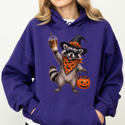 May include: A deep purple hooded sweatshirt featuring a graphic of a raccoon wearing a black witch hat with a small pumpkin, heart-shaped sunglasses, and an orange bandana with black bats. The raccoon holds an iced coffee and a pumpkin bucket.