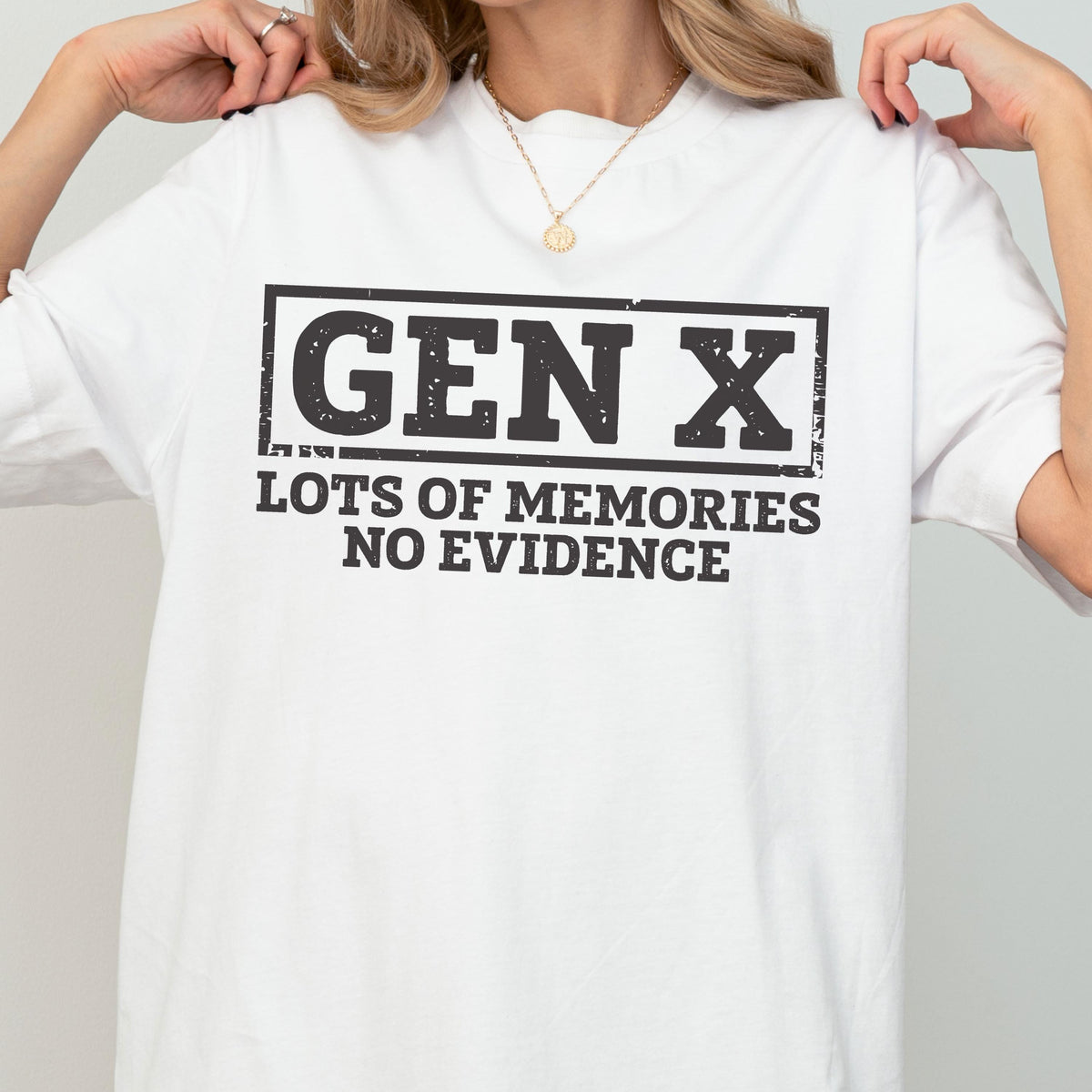 May include: A white short-sleeved t-shirt featuring a black rectangular graphic with the text "GEN X" in a bold, distressed font. Below the rectangle, the text "LOTS OF MEMORIES NO EVIDENCE" is printed in a matching black, distressed sans-serif font.