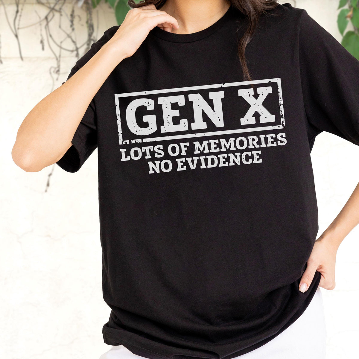May include: A black short-sleeved t-shirt featuring a white rectangular graphic with a distressed texture. The text inside the box reads GEN X, followed by the text LOTS OF MEMORIES NO EVIDENCE printed in a bold, sans-serif white font.