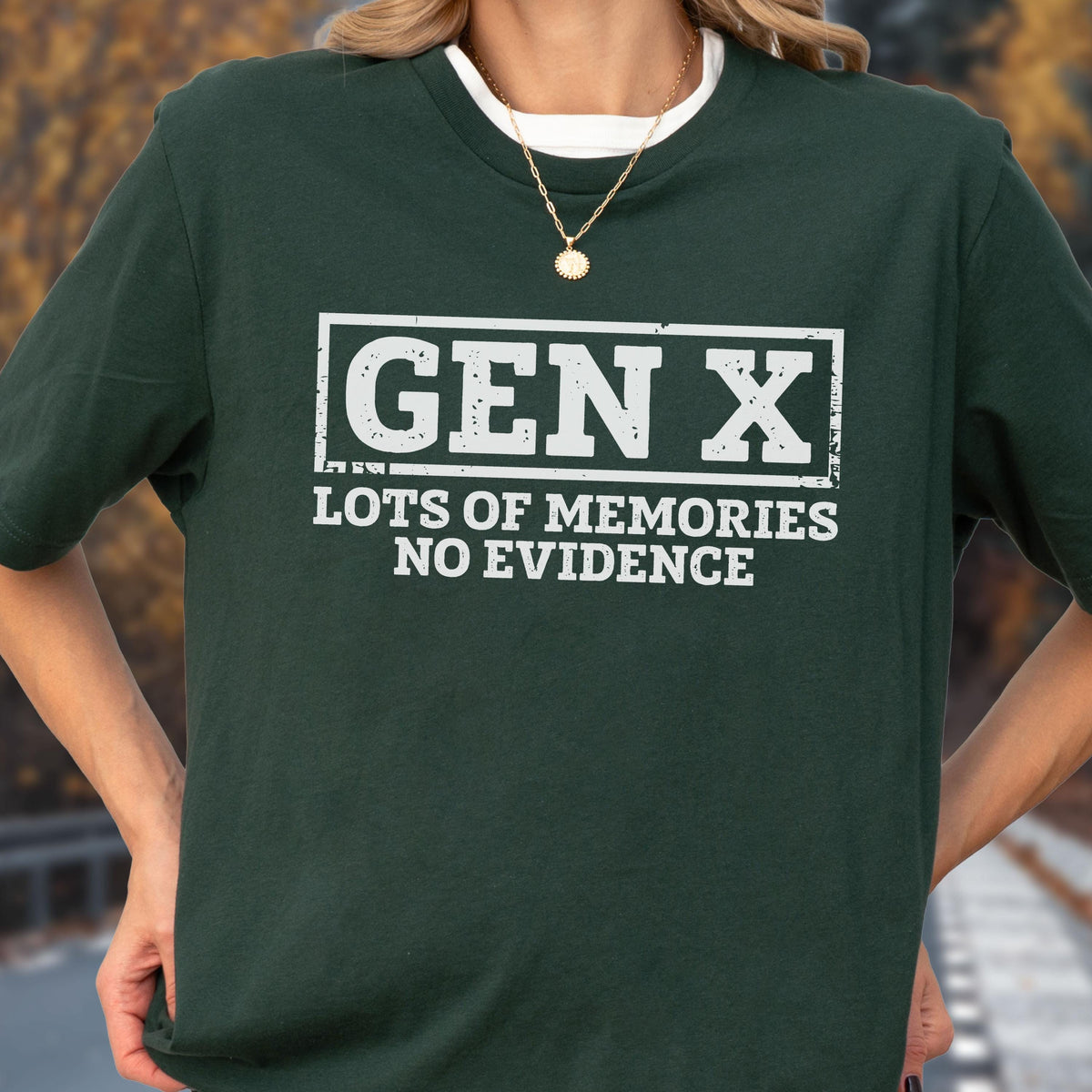 May include: A dark forest green short-sleeved t-shirt featuring white screen-printed text that reads GEN X inside a rectangular border, with the additional text LOTS OF MEMORIES NO EVIDENCE printed directly underneath in a bold, sans-serif font.