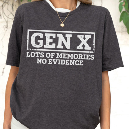 May include: A dark charcoal gray short-sleeved t-shirt featuring a white rectangular graphic with the text GEN X in a bold, distressed font, followed by the text LOTS OF MEMORIES NO EVIDENCE in a clean, sans-serif typeface below the box.