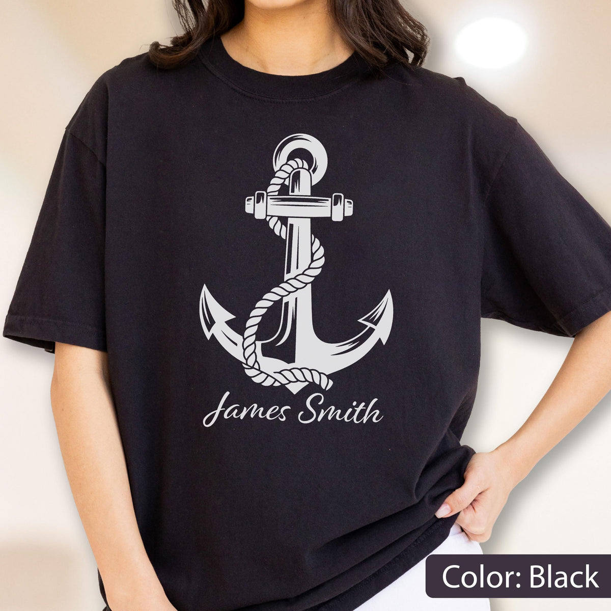 May include: A black short-sleeved t-shirt featuring a large white graphic of a nautical anchor wrapped in a rope. Below the anchor, the name James Smith is printed in a white cursive script font. The shirt has a crew neckline and a standard fit.
