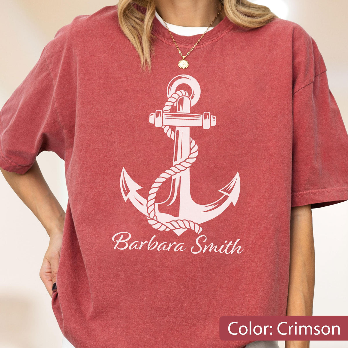 May include: A crimson short-sleeved t-shirt featuring a large white graphic of a ship anchor wrapped in rope. The text "Barbara Smith" is printed in white cursive lettering directly below the anchor design on the front of the garment.