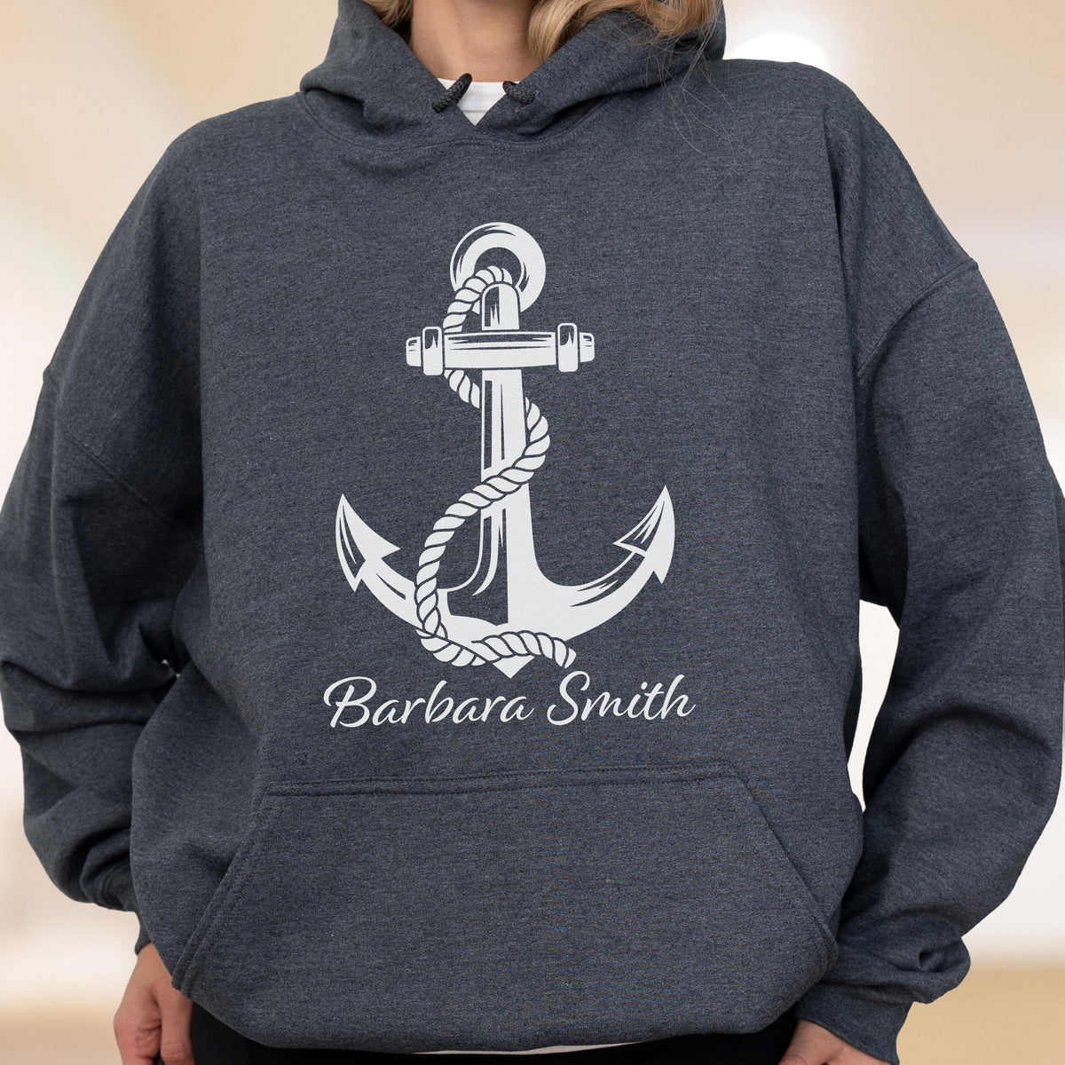May include: A dark charcoal gray hooded sweatshirt featuring a large white graphic of a nautical anchor wrapped in rope. Below the anchor, the name Barbara Smith is printed in a white cursive script font. The hoodie includes a front kangaroo pocket.