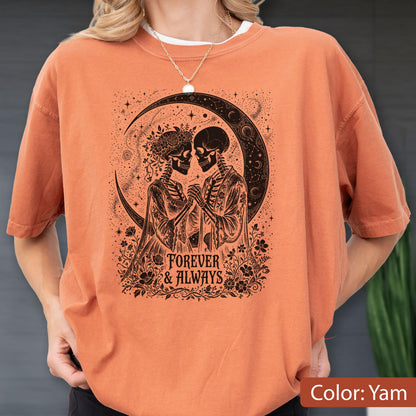 May include: A yam-colored short-sleeve t-shirt featuring a black graphic print of two skeletons holding hands under a crescent moon. The design includes floral accents and the text "FOREVER & ALWAYS" centered below the figures in a decorative font.