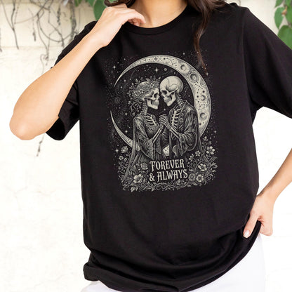May include: A black t-shirt featuring a graphic print of two skeletons facing each other, holding hands, and surrounded by flowers and a crescent moon. The text "FOREVER & ALWAYS" is printed in a white serif font below the skeletons.