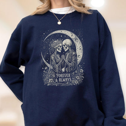 May include: A navy blue crewneck sweatshirt featuring a graphic print of two skeletons holding hands in front of a crescent moon. The design includes floral accents and the text "FOREVER & ALWAYS" in a white, stylized font centered below the figures.