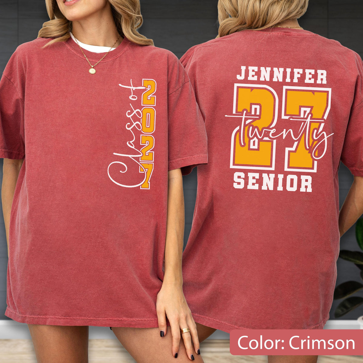 May include: A crimson short-sleeve t-shirt featuring white and yellow graphics. The front displays the vertical text Class of 2027. The back features the name Jennifer, the large number 27, the word twenty in script, and the word SENIOR.