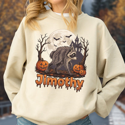 May include: A cream-colored crewneck sweatshirt featuring a graphic of a raccoon walking in front of a full moon, a haunted house, bare trees, and three jack-o'-lanterns. The name Jimothy is printed below the graphic in orange dripping letters.