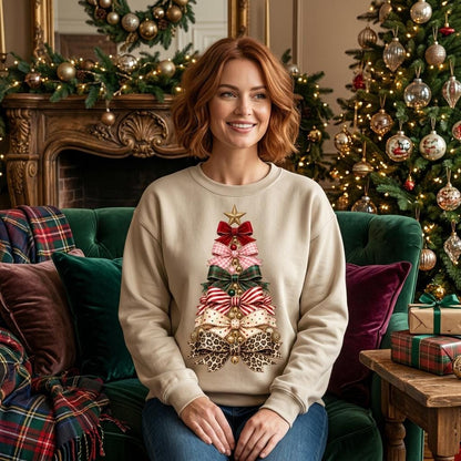 May include: A beige crewneck sweatshirt featuring a graphic of a Christmas tree constructed from stacked bows in various patterns, including red velvet, plaid, polka dots, and leopard print, topped with a gold star and small gold ornaments.