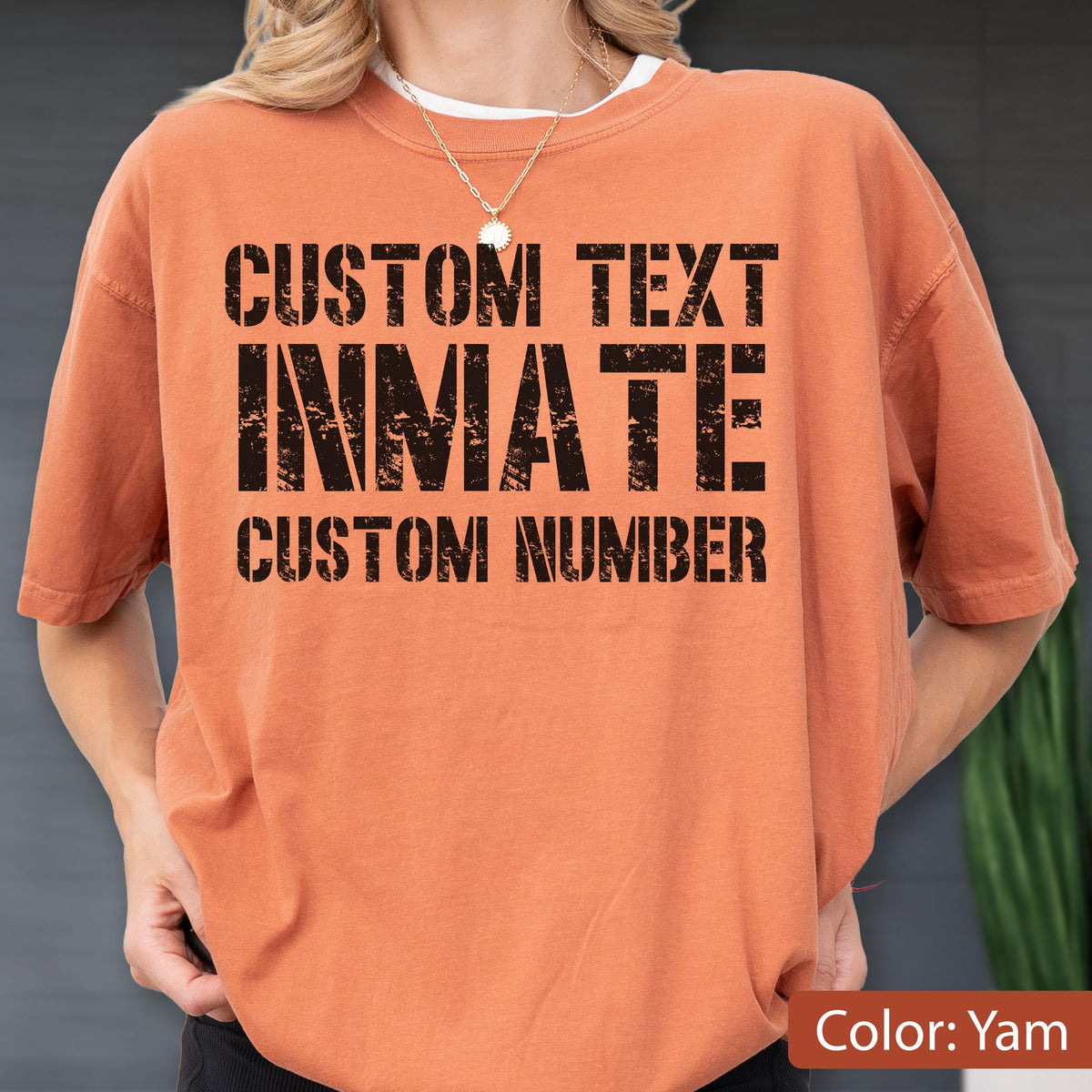 May include: A yam-colored short-sleeve t-shirt featuring black distressed-style text that reads CUSTOM TEXT, INMATE, and CUSTOM NUMBER. The shirt has a crew neckline and a relaxed fit, showcasing a bold graphic design printed on the front chest area.