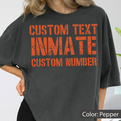 May include: A pepper-colored short-sleeve t-shirt featuring distressed orange block lettering on the front. The text reads CUSTOM TEXT, INMATE, and CUSTOM NUMBER in a bold, weathered font style across the chest area of the garment.