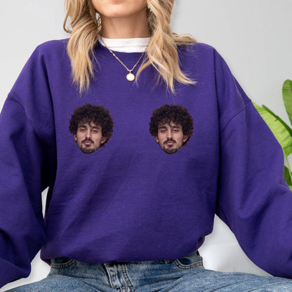 May include: A deep purple long-sleeve sweatshirt featuring two identical photographic prints of a person with dark curly hair and a mustache positioned on the chest area. The garment has a crew neckline and a relaxed fit, worn over a white shirt.