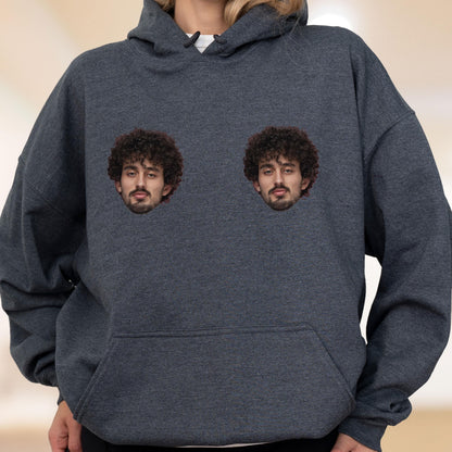 May include: A dark heather gray hooded sweatshirt featuring a front kangaroo pocket and two identical graphic prints of a person with dark curly hair and a beard positioned on the upper chest area of the garment.