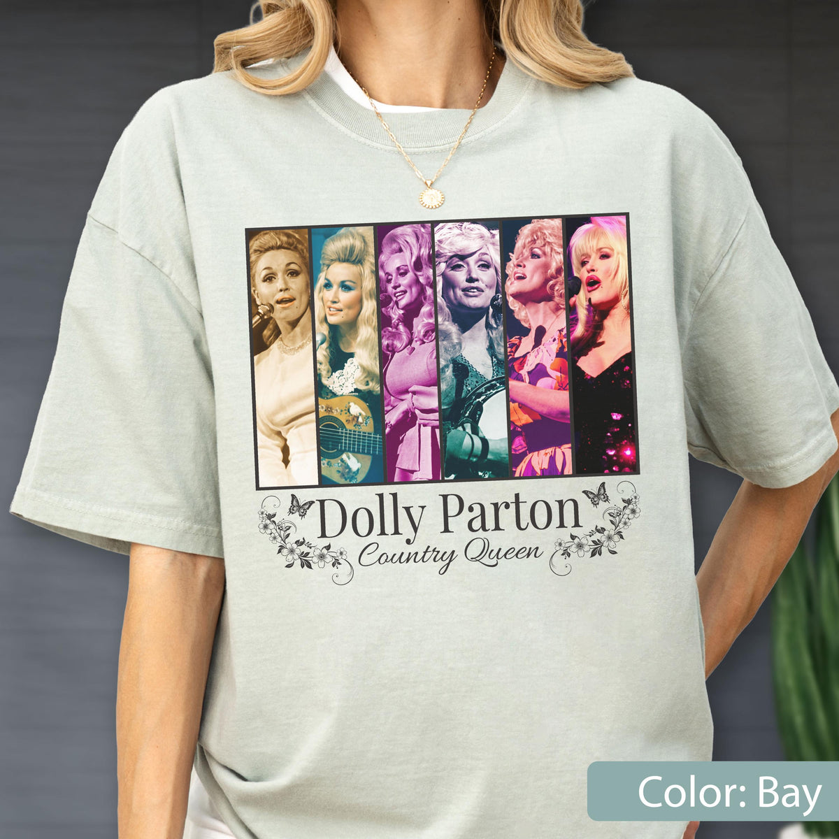 May include: A light sage green short-sleeve t-shirt featuring a rectangular graphic with six distinct portraits of Dolly Parton. Below the images, the text reads Dolly Parton Country Queen, framed by decorative floral and butterfly illustrations.