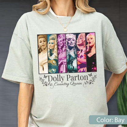 May include: A light sage green short-sleeve t-shirt featuring a rectangular graphic with six distinct portraits of Dolly Parton. Below the images, the text reads Dolly Parton Country Queen, framed by decorative floral and butterfly illustrations.