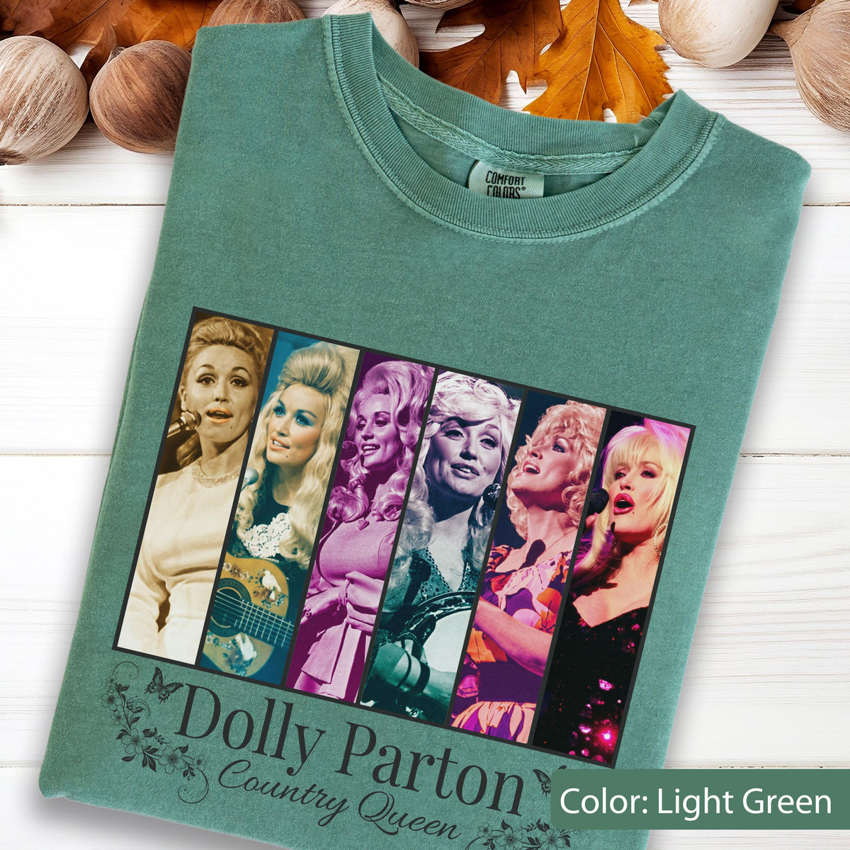 May include: A light green t-shirt featuring a graphic print of six vertical panels displaying various images of Dolly Parton. Below the graphic, the text reads Dolly Parton Country Queen in a decorative font, accompanied by small floral illustrations.