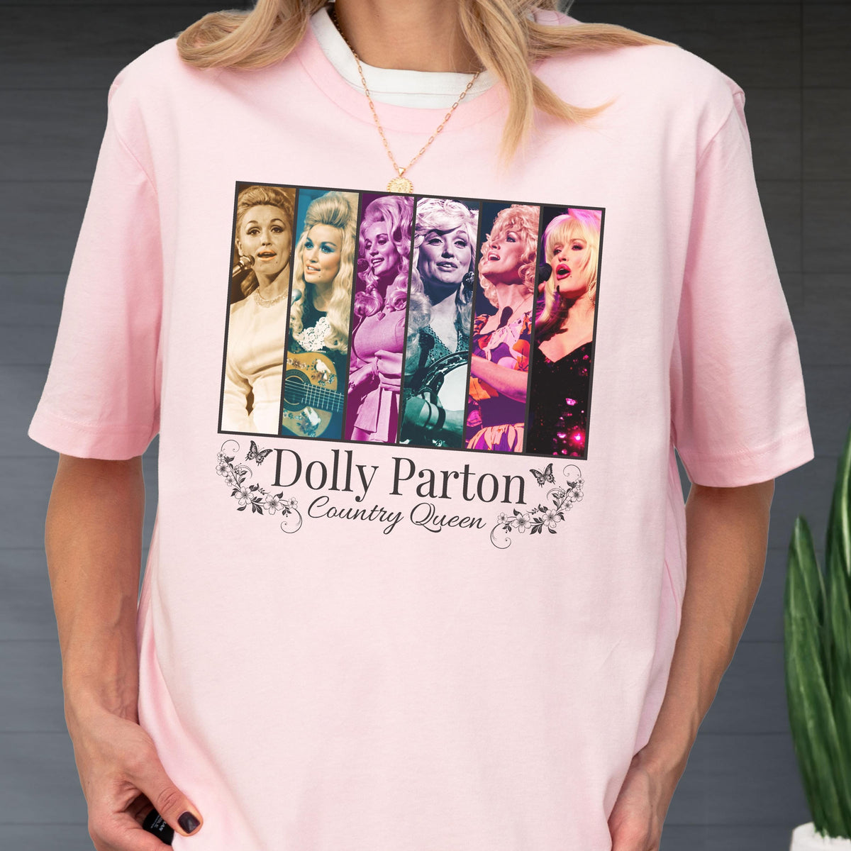 May include: A light pink short-sleeved t-shirt featuring a rectangular graphic with six distinct portraits of Dolly Parton in various color tones. Below the images, the text reads Dolly Parton Country Queen, framed by small floral and butterfly motifs.
