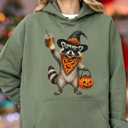 May include: An olive green hooded sweatshirt featuring a graphic of a raccoon wearing a black witch hat with a small pumpkin, heart-shaped sunglasses, and an orange bandana with black bats. The raccoon holds an iced coffee and a pumpkin bucket.